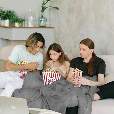 Family enjoying popcorn during a cozy movie night under a fleece blanket